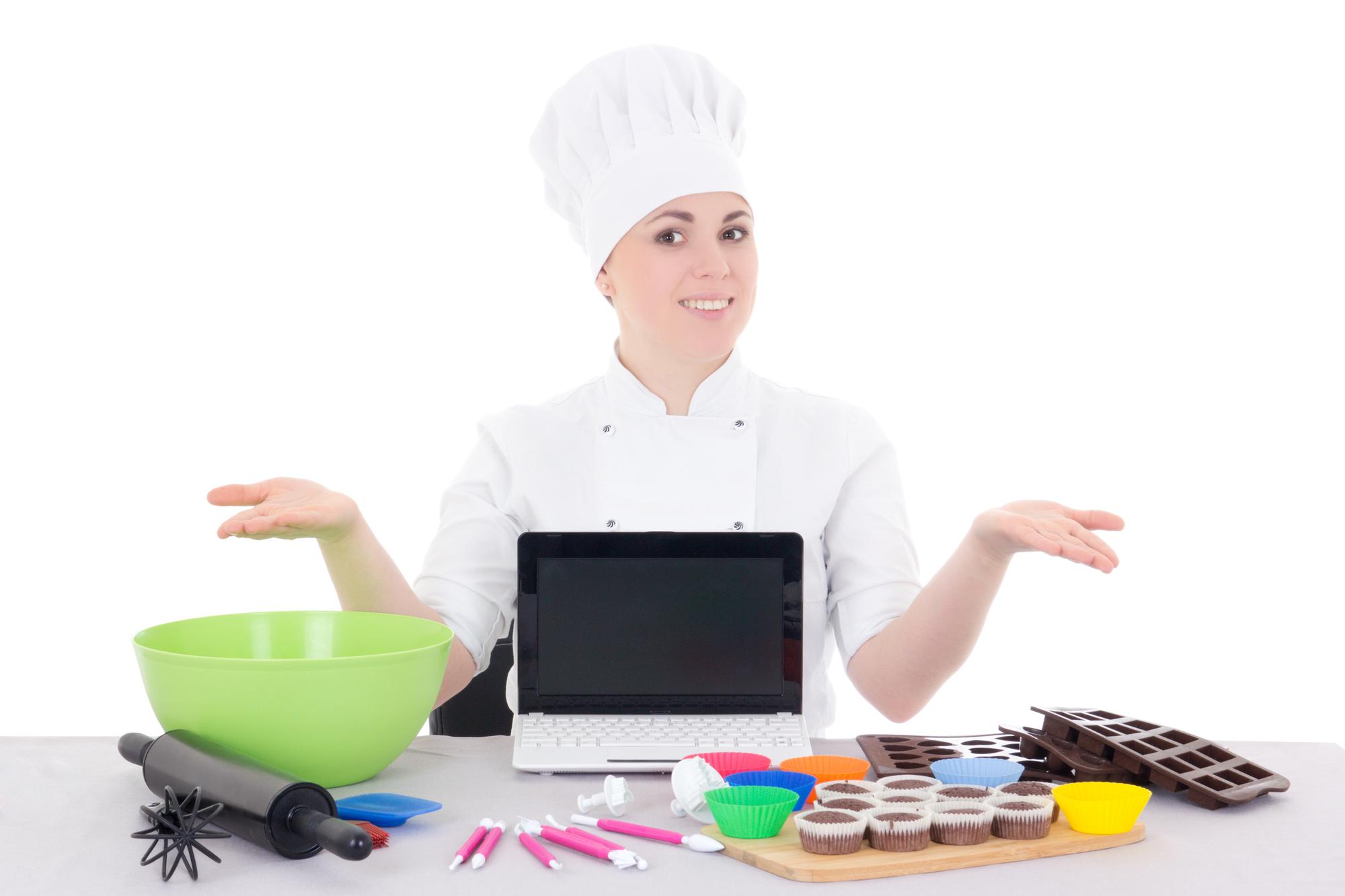 Chef online che insegna sorridendo davanti a laptop e piatti colorati
